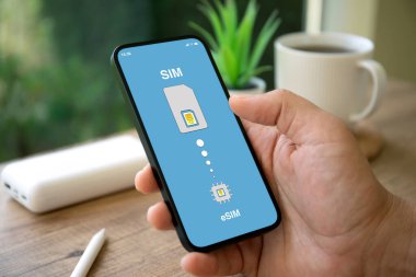 Ofisteki kafenin eSim arka planında Sim kartı değiştirilmiş erkek el telefonu