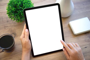 Kadın elleri bilgisayarın tabletini tutarken arka planda izole ahşap masa ofis içinde.