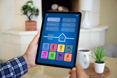 Man eller bilgisayar tabletini akıllı ev uygulaması ile birlikte apartmandaki masanın ekran arka planında tutar