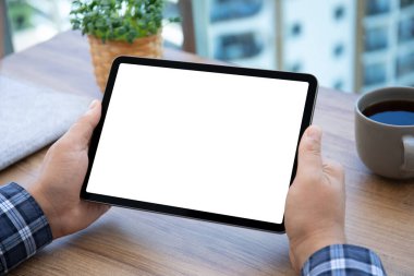 Erkek eller bilgisayar tabletini, ofisteki izole ekranlı ahşap masadan tutuyor.