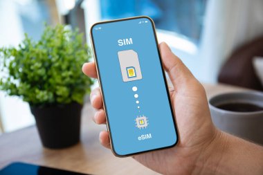Ofisteki kafenin eSim arka planında Sim kartı değiştirilmiş erkek el telefonu