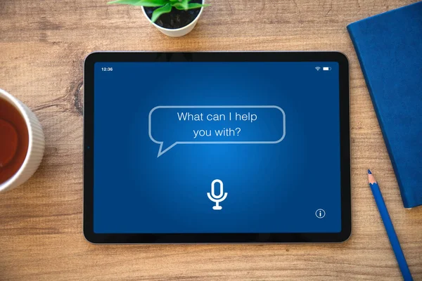 Uygulama kişisel asistanı olan bilgisayar tableti ekranda ahşap masa ve mavi not defteri