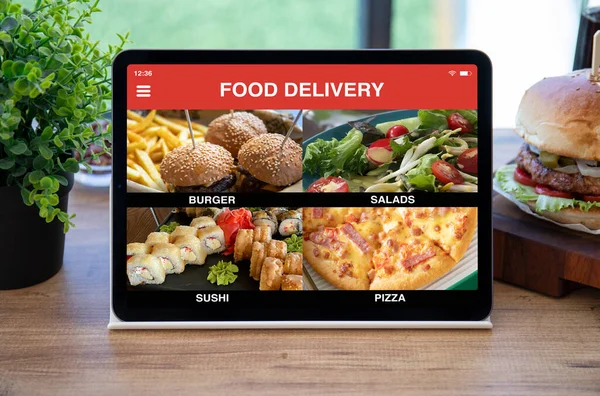 computer tablet with app food delivery on screen over table in cafe