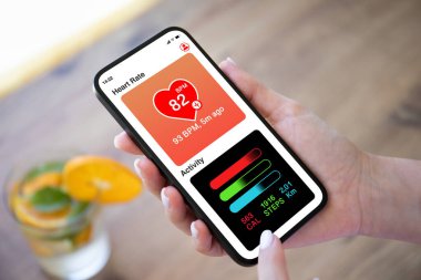 Kadın cep telefonu uygulamalı ve portakallı limonatanın arka planında etkinlik var.