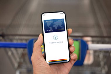 Süpermarke alışveriş arabasının üzerindeki ekranda yüz tarama kimliğiyle el ele tutuşan bir adam.