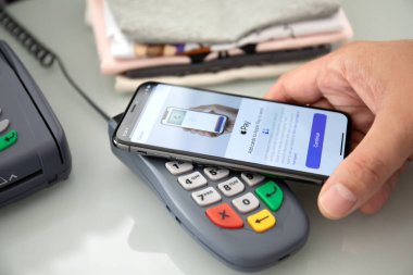 Alanya, Türkiye - 12 Ağustos 2019: Apple iPhone X 'te Apple Pay ile el ele tutuşan adam ve POS ödeme çevrimiçi terminali. iPhone Apple tarafından oluşturuldu ve geliştirildi.
