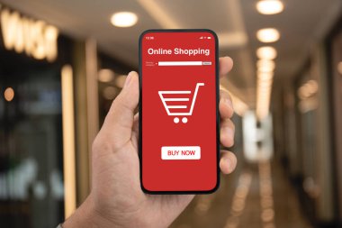 Adam cep telefonu uygulamalı sokak lambasındaki vitrinlerin ekranında online alışveriş yapıyor.