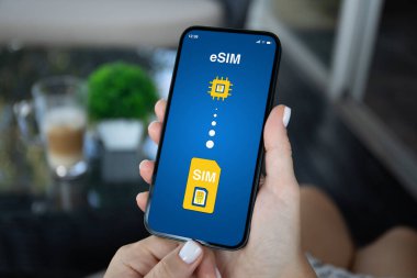 eSim 'de Sim kartının değiştirildiği kadın telefonu kafe ofisinde ekranda.  