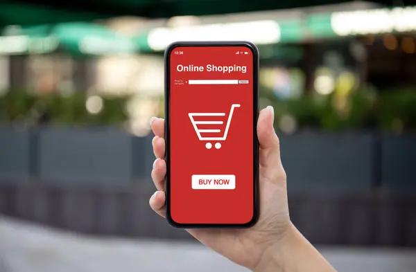 Woman hand hold phone with online shopping app background of street with store