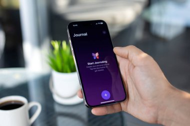 Alanya, Türkiye - 1 Aralık 2023: Man hand holding iPhone 15 Pro Max with home screen Journal Apple app