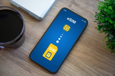 Ofisteki ahşap masanın eSim ekran arka planında Sim kart değiştirme ile telefon  