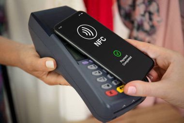 Mağazadaki posizyon terminali üzerinden ücretli kablosuz internet teknolojisi olan kadın eller telefonu tutuyor.