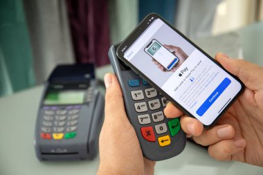 Alanya, Türkiye - 12 Ağustos 2019: Apple iPhone X 'te Apple Pay ile el ele tutuşan adam ve POS ödeme çevrimiçi terminali. iPhone Apple tarafından oluşturuldu ve geliştirildi.