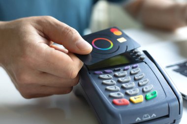 Alanya, Türkiye - 4 Nisan 2024: Plastik kart tutan ve çevrimiçi POS terminaline geçiş kartı ödeyen adam.