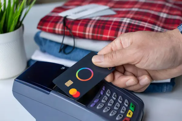 stock image Alanya, Turkey - April 16, 2024: Man hand holding plastic card Payoneer Mastercard and pay pass online POS terminal.