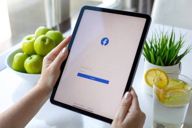 Alanya, Türkiye - 31 Mayıs 2024: Ekranda sosyal ağ hizmetleri kuryesi Facebook ile iPad Air ile el ele tutuşan kadın.