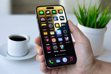 Alanya, Türkiye - 6 Temmuz 2024: Elle tutulan Apple iPhone 15 Pro Max ile ana ekran IOS 18 ekranda.