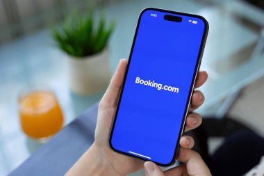 Alanya, Türkiye - 21 Temmuz 2024: Apple iPhone 15 Pro Max 'i elinde tutan adam ekrana internetten otel rezervasyonu yaptırıyor.