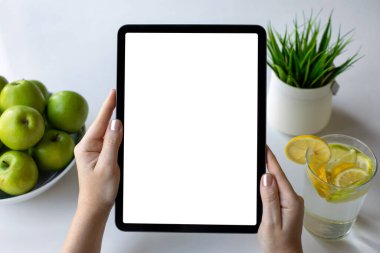 Kafe 'de yeşil elmalı masanın izole ekran arka planına sahip bilgisayar tabletini tutan kadın elleri