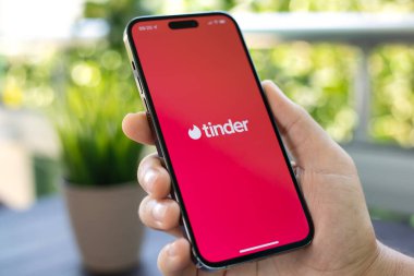 Alanya, Türkiye - 31 Temmuz 2024: Elleri Apple iPhone 15 Pro Max ile çevrimiçi internet ağı hizmetleri Tinder ekranda.