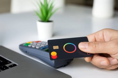 Alanya, Türkiye - 4 Nisan 2024: Elde plastik kart tutan Payonetici Mastercard ve dizüstü bilgisayar Apple Macbook çevrimiçi POS terminal geçiş kartı .