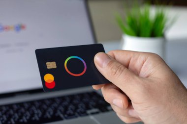 Alanya, Türkiye - 4 Nisan 2024: Elde plastik kart tutan Payonetici Mastercard ve dizüstü bilgisayar Apple Macbook çevrimiçi POS terminal geçiş kartı