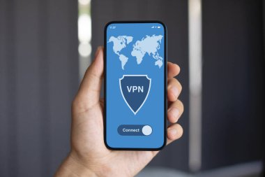 VPN uygulamalı erkek el bilgisayarı. Arka planda karanlık duvar.