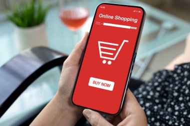 Kadın eli telefonu internetten alışveriş uygulaması ile kafedeki bir bardak şarabın arka planında tutuyor.