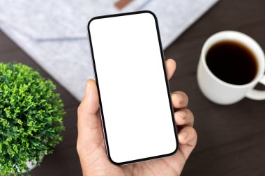 Ofiste, arka planda izole edilmiş ahşap masası olan erkek eli telefon.