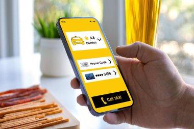 Erkek el ele telefon ve taksi çağırma uygulaması ekran arkasındaki masada bira ve kafede atıştırmalıklar.