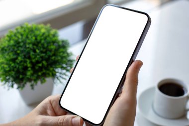 Kadın eli telefonu, kafeteryada kahveli masaya yaslıyor.