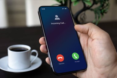 Erkek el ele telefon, ekranda gelen arama, ofiste kahve.