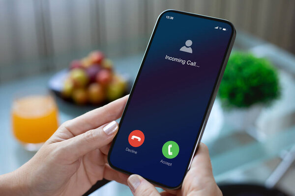 женские руки держат телефон с входящим звонком на экране фонового стола в кафе