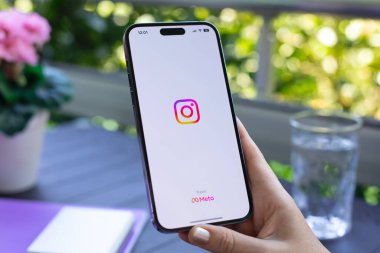 Alanya, Türkiye - 17 Ağustos 2024: Elma iPhone 15 Pro Max 'i sosyal ağ servisi Instagram ile elinde tutan kadın ekranda.