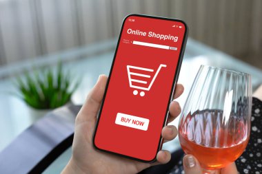 Kafede arka plandaki şarap kadehinde internetten alışveriş uygulaması olan kadın el ele tutuşması.