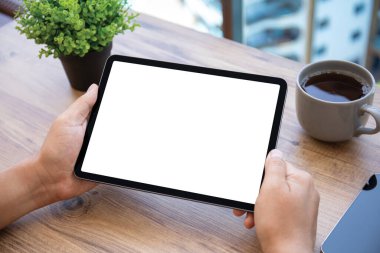 Erkek eller bilgisayarın tabletini tutarken arka planda izole edilmiş ahşap masa ofiste.