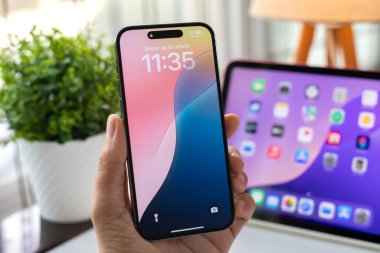 Alanya, Türkiye - 1 Ekim 2024: Apple iPhone 15 Pro Max ve iPad 'in ana ekran iOS ve iPadOS 18 AI Apple Intelligence Siri ile el ele tutuşması.
