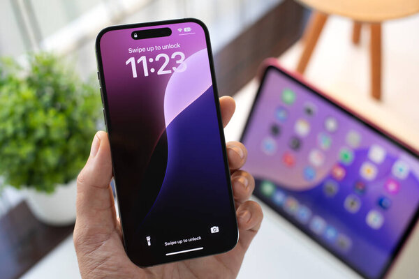 Alanya, Turkey - October 1, 2024: Man hand holding Apple iPhone 15 Pro Max and  iPad with home screen iOS and iPadOS 18 AI Apple Intelligence Siri on the screen.