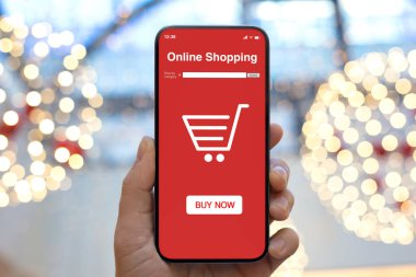 Bayram ışıklarının ekranında kırmızı çevrimiçi alışveriş uygulaması olan erkek el bilgisayarı. 