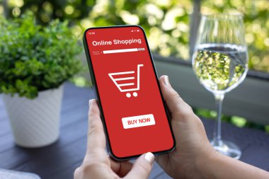 Kadın elleri ekrandaki kafeterya arka planında kırmızı online alışveriş uygulaması olan telefonu tutuyor.