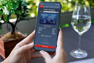 Kadın eli ekrandaki kafeterya arka planında online alışveriş uygulaması olan telefonu tutuyor.