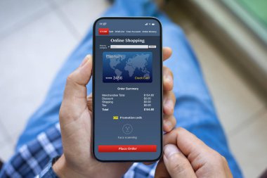 Ekranda online alışveriş uygulaması olan erkek eller telefonu tutuyor