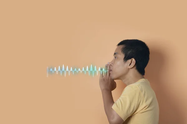 Young man whispering a secret behind hand with sound waves. Audio sound equalizer technology. Secret, gossip concept. orange studio background.