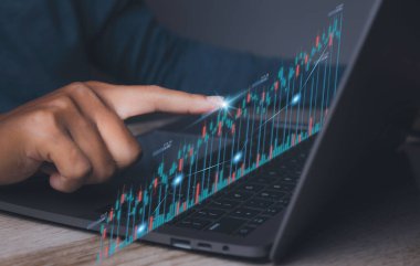 Stock Market Investments analysis and Digital Assets. Business finance technology and investment concept. Stock market graph with man working on laptop stock trading computer screen background.