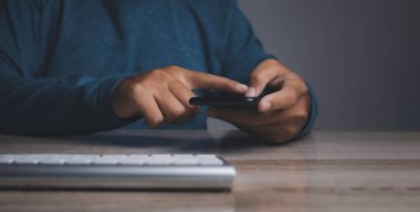 Akıllı telefon kullanan genç bir adam. El ele tutuşan cep telefonu mesajlaşması bizimle iletişim kuruyor. Sohbet ediyor, internet bilgilerini araştırıyor. Teknoloji aygıtı iletişimi.