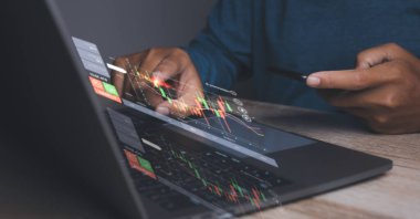 Stock Market Investments analysis and Digital Assets. Business finance technology and investment concept. Stock market graph with man working on laptop stock trading computer screen background.