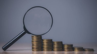 Büyüteçle büyüyen madeni paralar. Tasarruf ve bileşik çıkarlar kavramı.