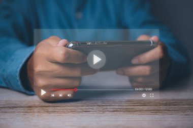 Cep telefonuyla video oyunu oynayan bir adam. Akıllı telefonlu çevrimiçi film yayını. İnternette hayali bir video oynatıcı servisi ile video izleyen kişi.
