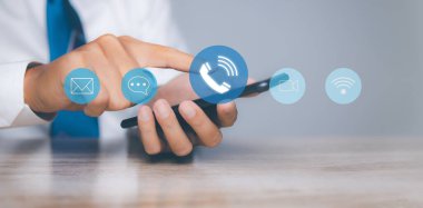 CONTACT US, İş adamı cep telefonu destek hattını kullanan insanlar iletişim simgeleriyle (e-posta, adres, canlı sohbet, İnternet Wi-fi) bağlantı kuruyor. Müşteri hizmetleri çağrı merkezi konsepti. Boşluğu kopyala.