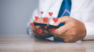 Genç adam internet paylaşımında sosyal medyadan kalp ikonuna akıllı telefon kullanıyor. Veri ve pazarlama konsepti. Cep telefonunda sosyal medya ve dijital.